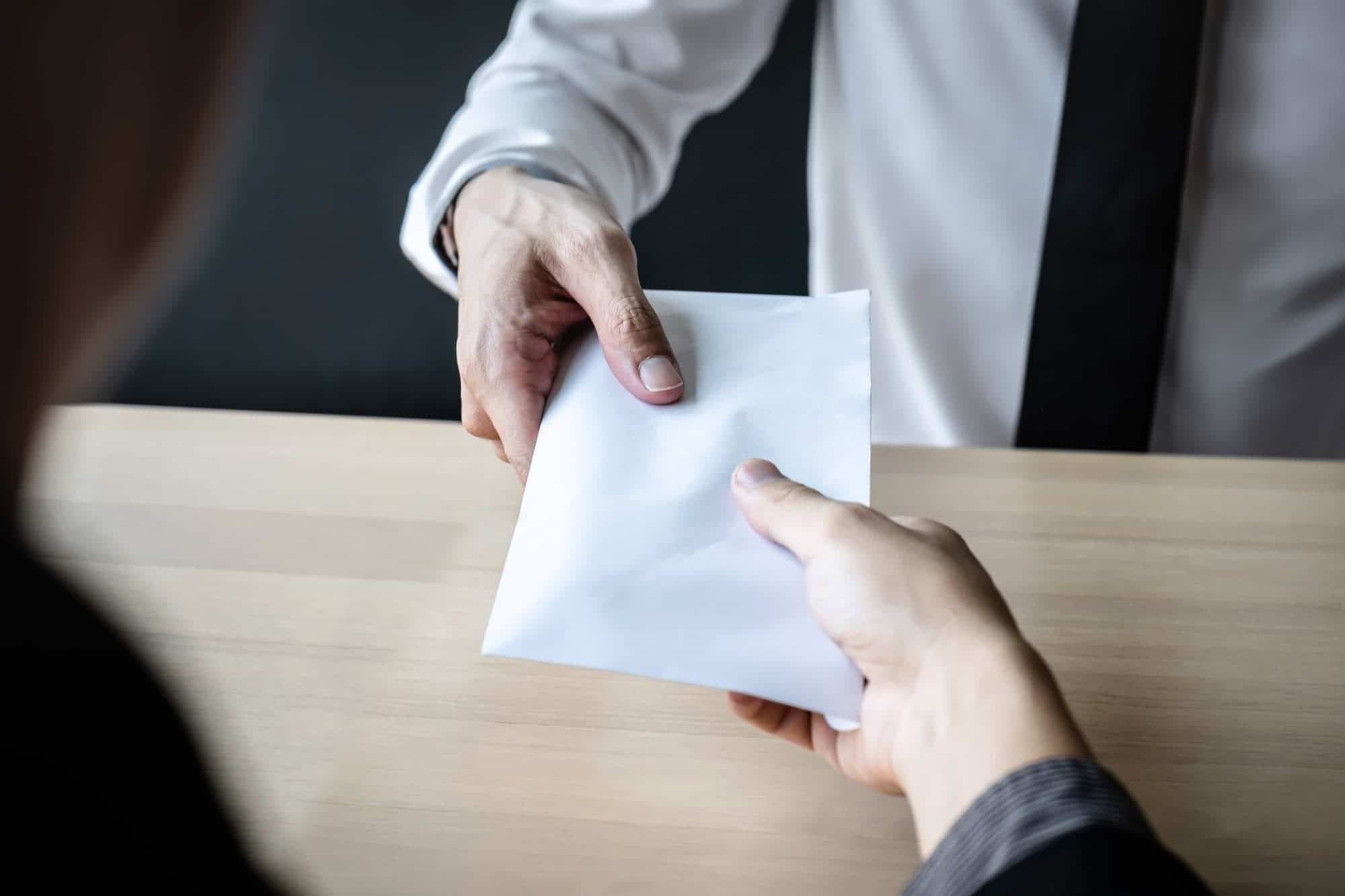 Photo de deux personnes échangeant une enveloppe de cash