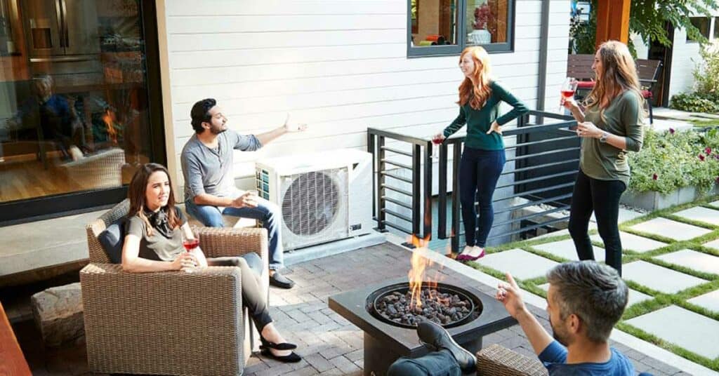 Groupe de personnes buvant un verre sur une terrasse a cote d’une thermopompe